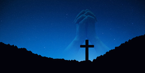 Silhouette of crucifix cross on mountain at night time with hand praying background.