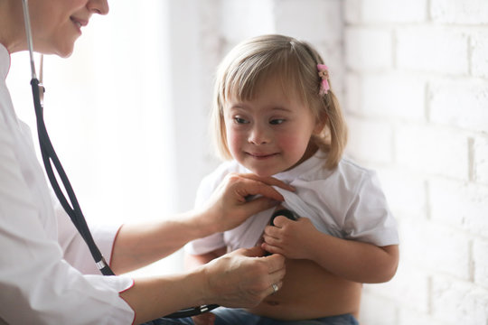 doctor listens heart of child with Down syndrome