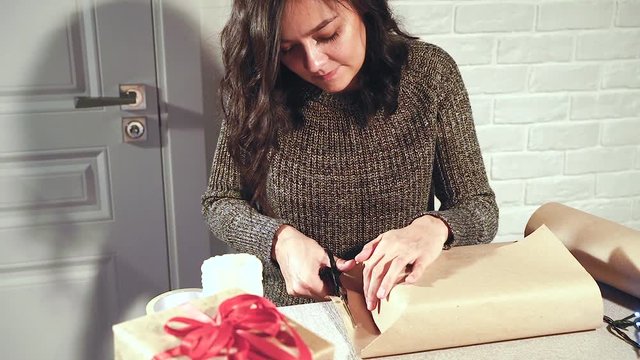 Preparing for the holiday. Young woman packing gifts.