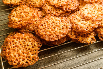 Freshly baked oatmeal lace cookies resting on oven rack.