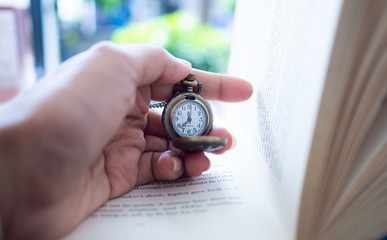 Hand holding watch locket and put it on old books. Concept  I want to keep it all the time in memory.