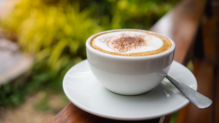 Coffee Cappuccino In white glass Makeup with bubbly cream Located on a wood near the natural light.