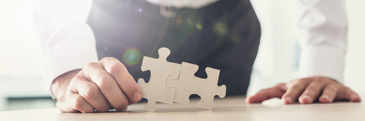 Wide view image of a businessman holding two puzzle pieces matched together