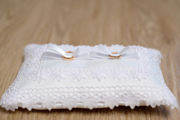 Two gold wedding rings on a white lace pillow