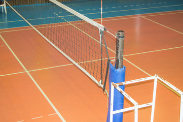 Empty sports hall with a stretched volleyball net and a tower for the judge