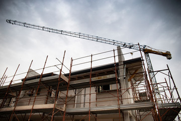 detail of a residential construction site with scaffolds and tower crane