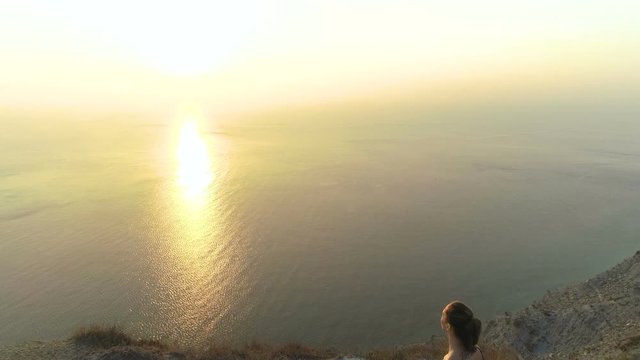 Beautiful view of woman doing yoga Baddha Konasana, Bound Angle Pose on the mountain with sea view at sunset.