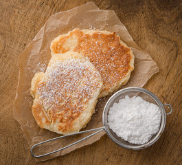 homemade pancakes with powdered sugar on wooden table