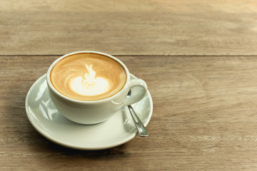 Cup of coffee with foam on wooden table.