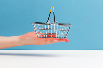 shopping cart trolley on hand  on white and blue  background. Side view. Shopping concept.
