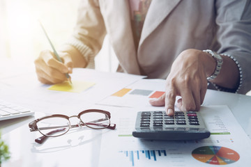 Close up of businessman or accountant hand holding pencil working on calculator to calculate...