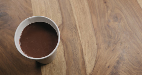 paper cup with hot cocoa on wood table with copy space