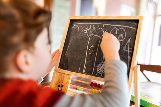Bambina che disegna sulla lavagna divertendosi