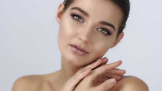 Beautiful young woman with clean fresh skin and perfect make-up touch own face . Facial treatment . Cosmetology , skin care, beauty and spa concept. Slow motion 4K UHD high quality sharp footage.