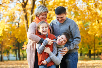 Happy family walks in autumn city park. Children and parents posing, smiling, playing and having fun. Bright yellow trees.