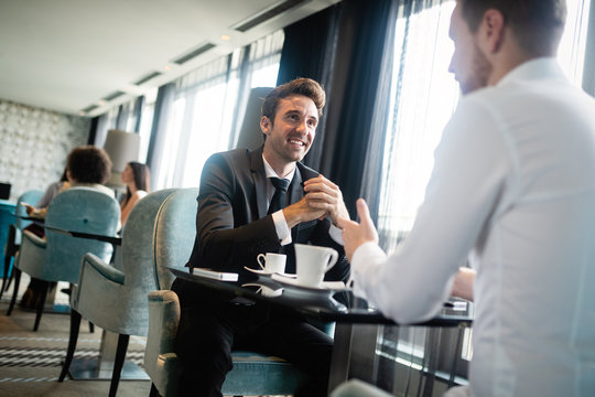 Two Business People Sitting At Coffee Shop Discussing Project