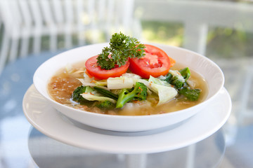 vegetable soup in a plate on a glass table