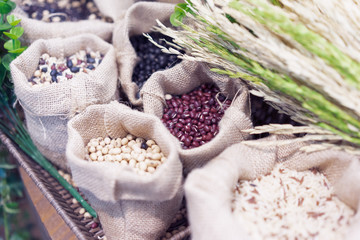 Grains, beans, grains and rice in a calico bag on a wooden table.