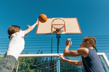 Streetball basketball game with two players, teenagers girl and boy, morning on basketball court