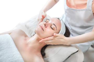 Fototapeta na wymiar Woman getting massage treatment at beauty spa salon. Female hands and face. Applying moisturizer to the skin. Facial skincare