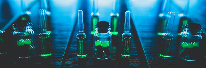 Pharmaceutical drugs banner. ampoules with green contents on a black background. opiate production concept