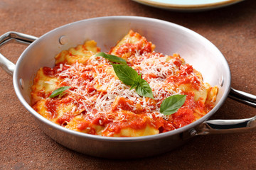 Pasta Italiana ravioli ripieni con salsa di pomodoro e parmigiano su tavolo di cucina,