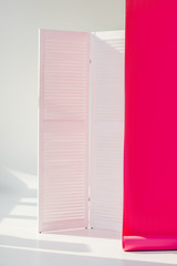 white room divider with bright pink rolled out wallpaper