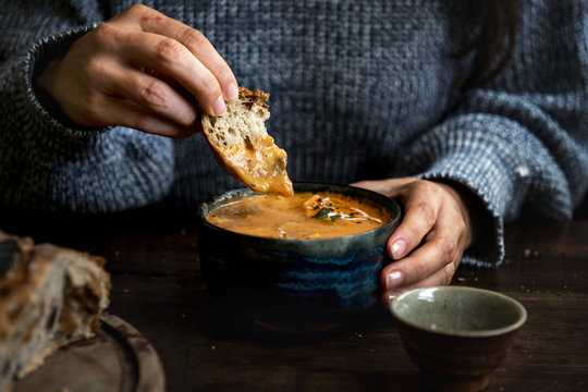 Woman dipping bread into a pumpkin soup