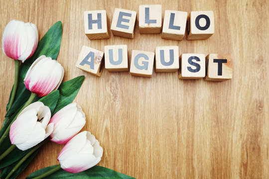 Hello August alphabet letter wooden cube with space copy on wooden background and flower decoration