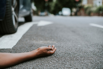 Person lying on the ground after a car accident