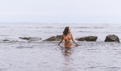 Beautiful woman in a orange bikini in the sea.