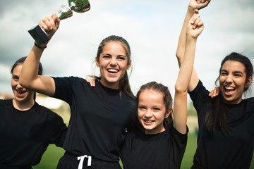 Young female football players celebrating their victory - obrazy, fototapety, plakaty