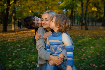 Fototapeta na wymiar Smiling young family into leaves on an autumns day