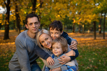 Fototapeta na wymiar Smiling young family into leaves on an autumns day