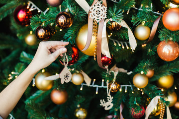 Female hand hangs on the Christmas tree wooden toy in the form of mittens. Preparing for the new year.