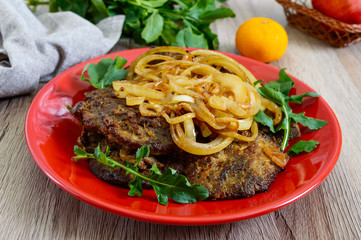 Juicy slices of fried liver and onions on a red plate.