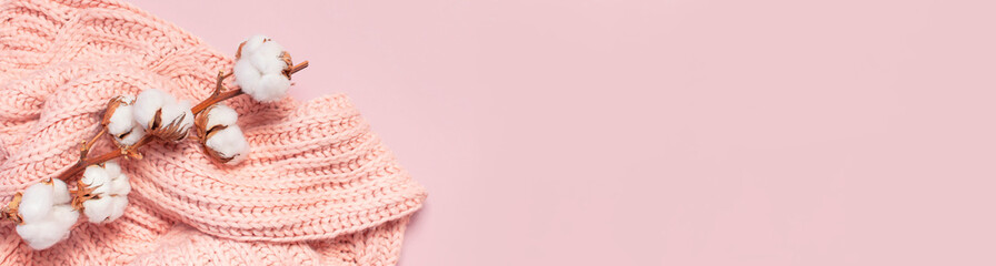 Female pink knitted sweater pullover and branch of cotton on pastel pink background top view flat...