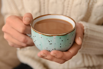Woman holding cup of aromatic coffee, closeup