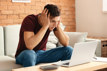 Fototapeta premium Troubled young man after making mistake while working with laptop at home