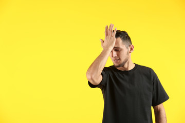 Emotional young man after making mistake on color background