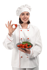 Young female chef with vegetables on white background