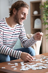 Young man doing jigsaw puzzle at home