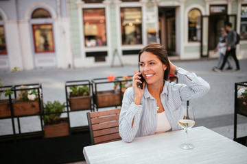 Beautiful young woman talking on the mobile phone in the cafe outdoors.