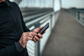 Senior man using smart phone outdoors. Close-up.