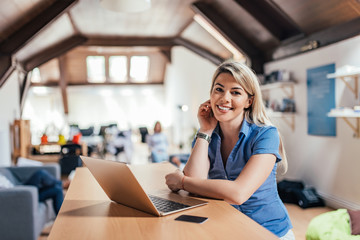 Portrait of young woman with laptop in open space company.