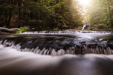 Brautpaar am Fluss im Wald, Wasser sitzend am Wasserfall im Sommer