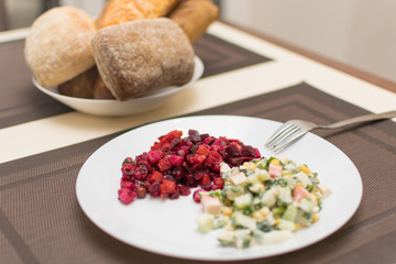 Two different salad vinaigrette and Olivier on a white plate.