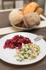 Two different salad vinaigrette and Olivier on a white plate.