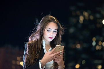 Woman using her cellphone at night in a city