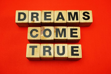 dream come true word created with cubes alphabet letters on red background